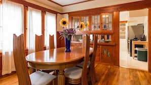 Un comedor con una mesa y sillas de madera, un jarrón con flores y armarios de madera.
