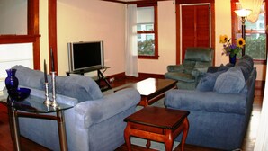 Una sala de estar con televisor, dos sofás, una mesa de centro y una lámpara.