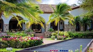 A courtyard with a billiards table, palm trees, and a building with arches and stone walls. - Casa Alegre, gorgeous villa in Rancho Santana! (Rancho Santana)