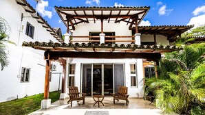 Una casa de dues plantes amb un porxo cobert, portes corredisses de vidre i un jardí petit.