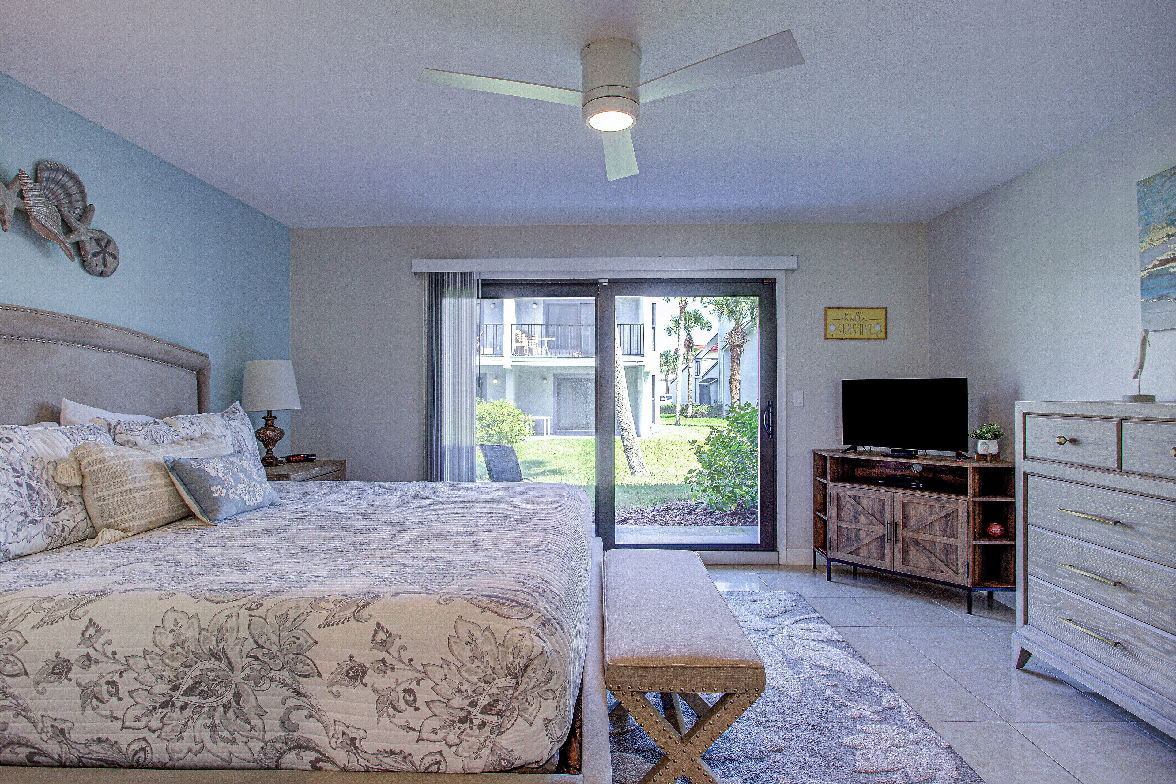 A bedroom with a bed, a bench, a TV, and a dresser.