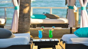 Quarto de hotel à beira-mar, com cama, uma mesinha com bebidas e vista para o oceano.