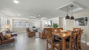 A spacious living area with a dining table, chairs, sofas, and a ceiling fan. - Island House Beach Resort V1 (Siesta Key)