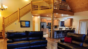 A spacious living area with a wooden staircase, a kitchen with wooden cabinets, and a dining area with bar stools.