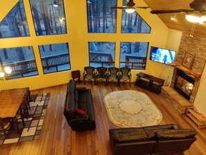 Un salon spacieux doté de grandes fenêtres, d’une cheminée et d’un téléviseur.