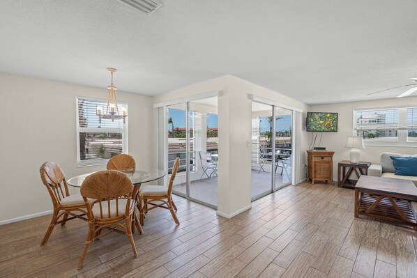 A spacious living area with a dining table and chairs, a sofa, and a television. - Island House Beach Resort V10B (Siesta Key)