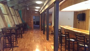 Ein Restaurant mit Holzböden, hohen Decken und einer langen Theke mit Barhocker.