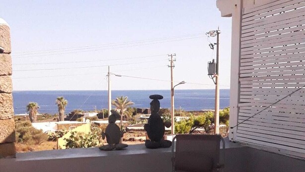 Une terrasse avec vue sur la mer, un mur en pierre et une structure en treillis blanc.