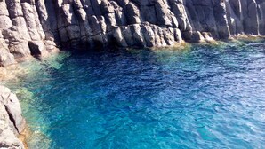 Une côte rocheuse bordée d’une eau d’un bleu limpide.
