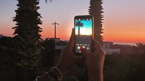 Une personne tenant un téléphone intelligent et admirant un coucher de soleil.