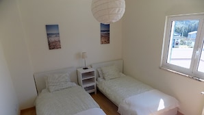 A bedroom with two single beds, a nightstand, a lamp, and two framed pictures on the wall. - Stunning Villa with Private Garden, Shared Pool, 10 min from lovely beach (Foz do Arelho)