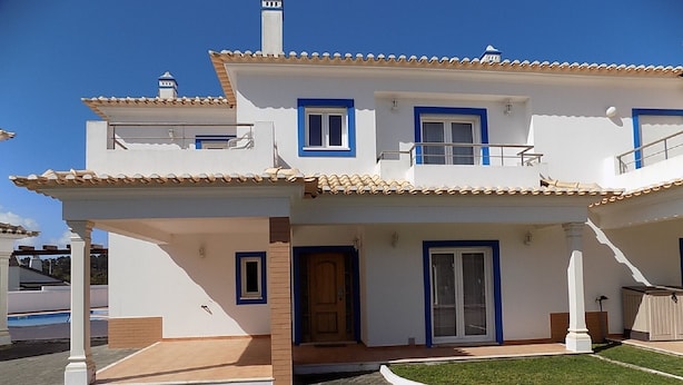 A two-story house with a tiled roof, a balcony, and a small front yard. - Stunning Villa with Private Garden, Shared Pool, 10 min from lovely beach (Foz do Arelho)