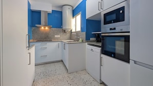 Cozinha compacta com armários brancos, forno embutido e micro-ondas.