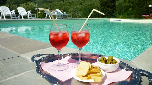 A poolside setting with two glasses of red drink, a tray with chips and olives, and a white umbrella. - Tuscany countryside appartment with pool (Reggello FI)