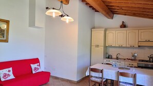 A kitchen with white cabinets, a red sofa, and a dining table with chairs. - Tuscany countryside appartment with pool (Reggello FI)