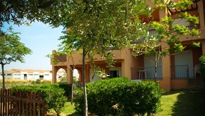 Un cortile con una recinzione in legno, un piccolo albero e un edificio con balconi e finestre.