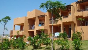 Un edificio a più piani con balconi, immerso nel verde.