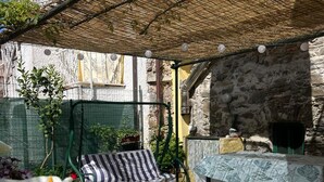 Un espace extérieur abrité, avec une table et des chaises, un mur en pierre et un barbecue.