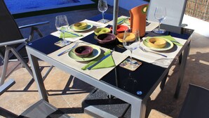 Un espace extérieur aménagé pour les repas, avec une piscine en arrière-plan.