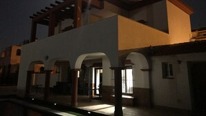Un bâtiment doté d’un balcon et d’arcades, sous un ciel nocturne où l’on peut voir la lune.