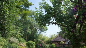 Ein Garten mit einem Gazebo, üppigem Grün und blühenden Pflanzen.