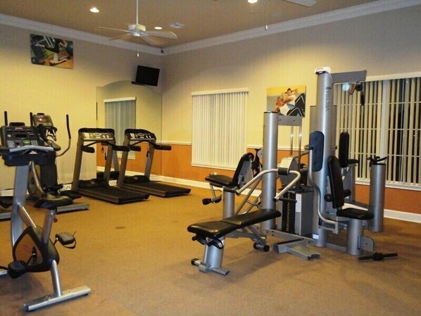Ein Fitnessraum mit Laufbändern, einer Hantelbank und einem Krafttrainer.