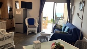 A modern living room with a sofa, a dining table, and a kitchen area with a fridge and oven. - Apartment/ flat - Collioure (Collioure)