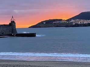 Un paysage côtier avec un phare, une mer calme et une ville située sur une colline.