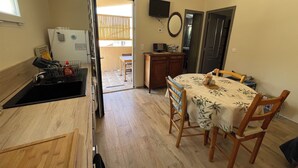 A compact kitchen with a sink, stove, and a dining area with a table and chairs. - house / villa - Monacia d'Aullène (Monacia-D'aullène)