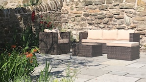 A stone wall, outdoor seating with cushions, and potted plants. - A delightful and historic property just a few steps from the harbour. (Pittenweem)