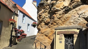 A narrow cobblestone street flanked by buildings with stone walls and red-tiled roofs. - A delightful and historic property just a few steps from the harbour. (Pittenweem)