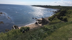A coastal landscape with a rocky beach, a paved walkway, and a grassy area. - A delightful and historic property just a few steps from the harbour. (Pittenweem)