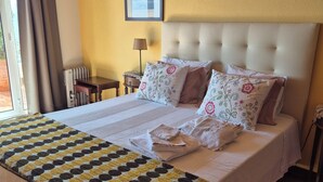 A neatly made bed with floral pillows, a bedside lamp, and a framed picture on the wall.