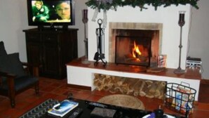 A living room with a fireplace, a television, and a coffee table with remote controls.
