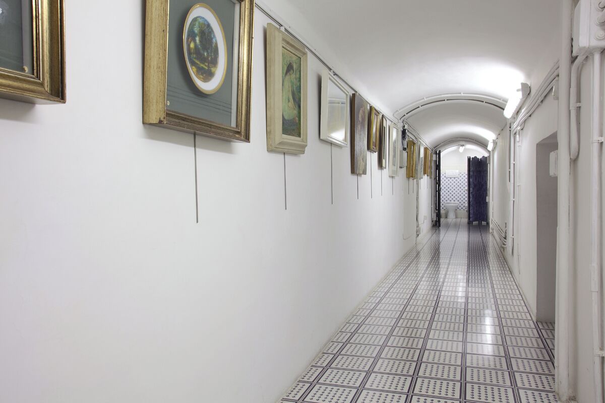 A corridor with framed artworks on the walls and a patterned floor.