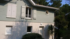 Una casa de dues plantes amb teulada a dos aigües, finestres laterals i una finestra circular al segon pis.