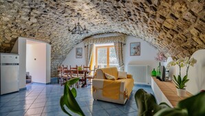 A cozy attic room with a stone ceiling, a sofa, a dining table, and a kitchen area. - Domus Le Postali, Lovely 2 bedroom beach apartment on Sorrento Coast (Vico Equense)