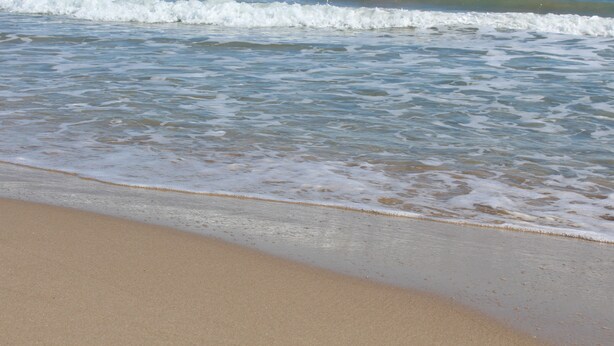Una playa con olas lamiendo suavemente la orilla.