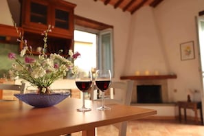 A dining table with a vase of flowers and two wine glasses.