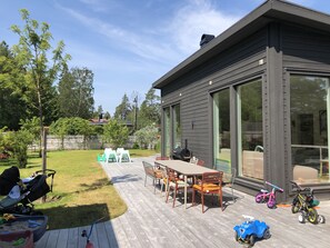 Ein modernes Haus mit Terrasse, Gartenmöbeln und Grill.