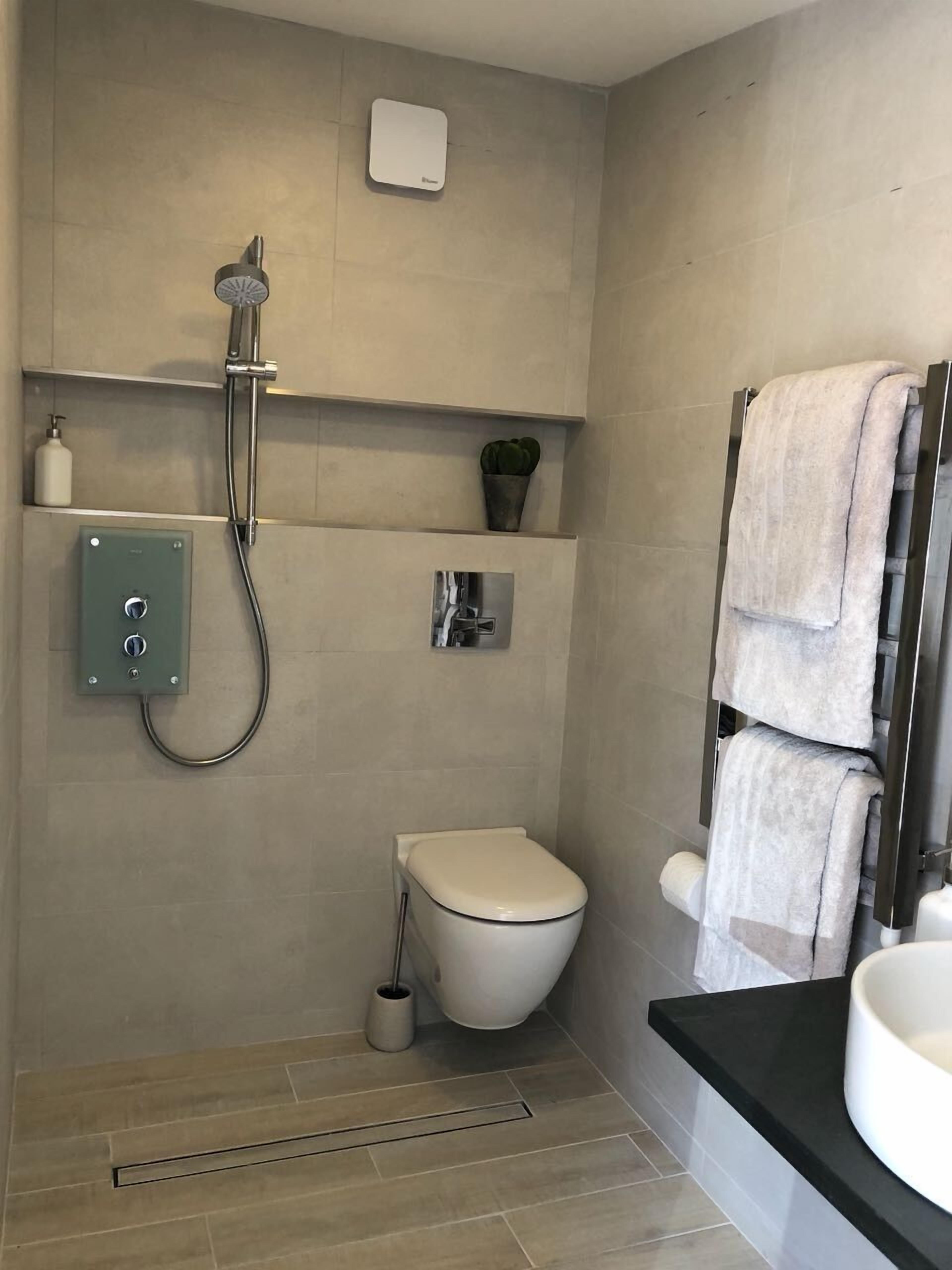 Une salle de bain moderne équipée d’une douche, de toilettes et d’un lavabo.