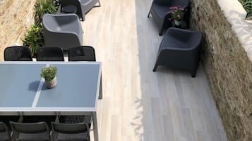 Enjoy dining or socializing in this serene patio area with a table and chairs, surrounded by lush greenery.