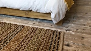 A wooden-paneled bedroom with a large bed, two bedside tables, and a woven rug. - Stylish Cottage, central location with harbour view and double parking (Salcombe)