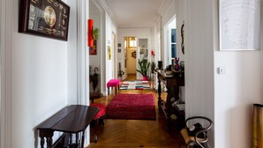 Un pasillo con un banco de madera, un tapete rojo y una obra de arte náutica enmarcada en la pared.
