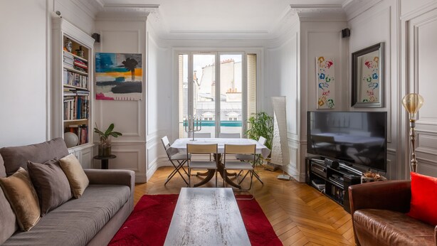 Una sala de estar con sofá, mesa de comedor, televisor y estantería.