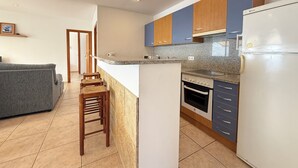 Eine moderne Küche mit einer zentralen Kochinsel, Holzbarhocker, einem Einbauofen und einem Kühlschrank.
