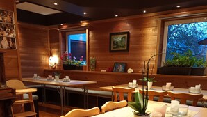 A restaurant with wooden walls, a long table with candles, and potted plants. - Farmhouse in a quiet location, workers' housing/farmhouse in a peaceful setting (Erlbach)
