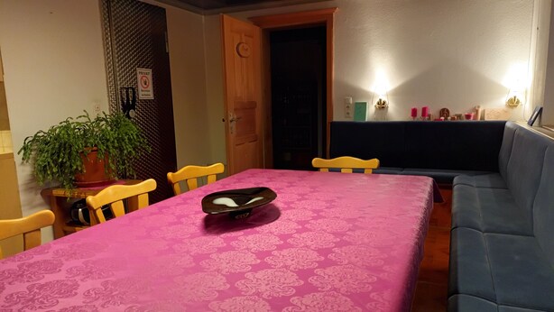 A dining area with a pink tablecloth, wooden chairs, a blue sofa, a potted plant, and a closed door labeled "PRIVATE." - Farmhouse in a quiet location, workers' housing/farmhouse in a peaceful setting (Erlbach)