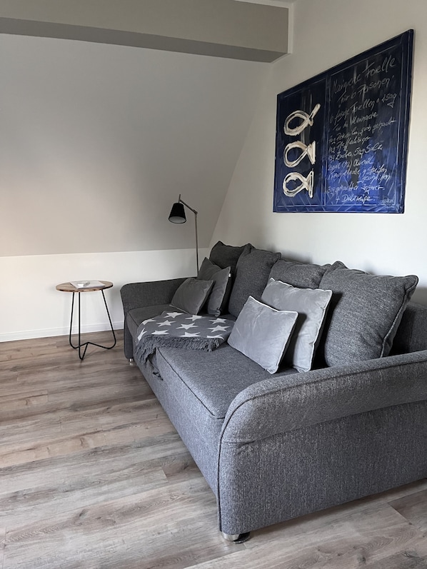 A modern living room with a grey sofa, a small round side table, and a floor lamp. - Cool, high-quality apartment on the Elbe, close to the city (Hamburg)