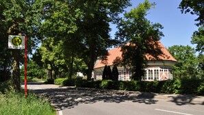 Un bâtiment avec un toit rouge, entouré d’arbres et de verdure.